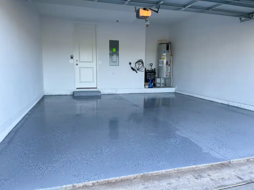 When Should You Install A Garage Floor Coating? Orlando, FL USA - June 28, 2021: A freshly painted with a gray epoxy finish sprinkled with blue, black and white plastic chips. Install A Garage Floor